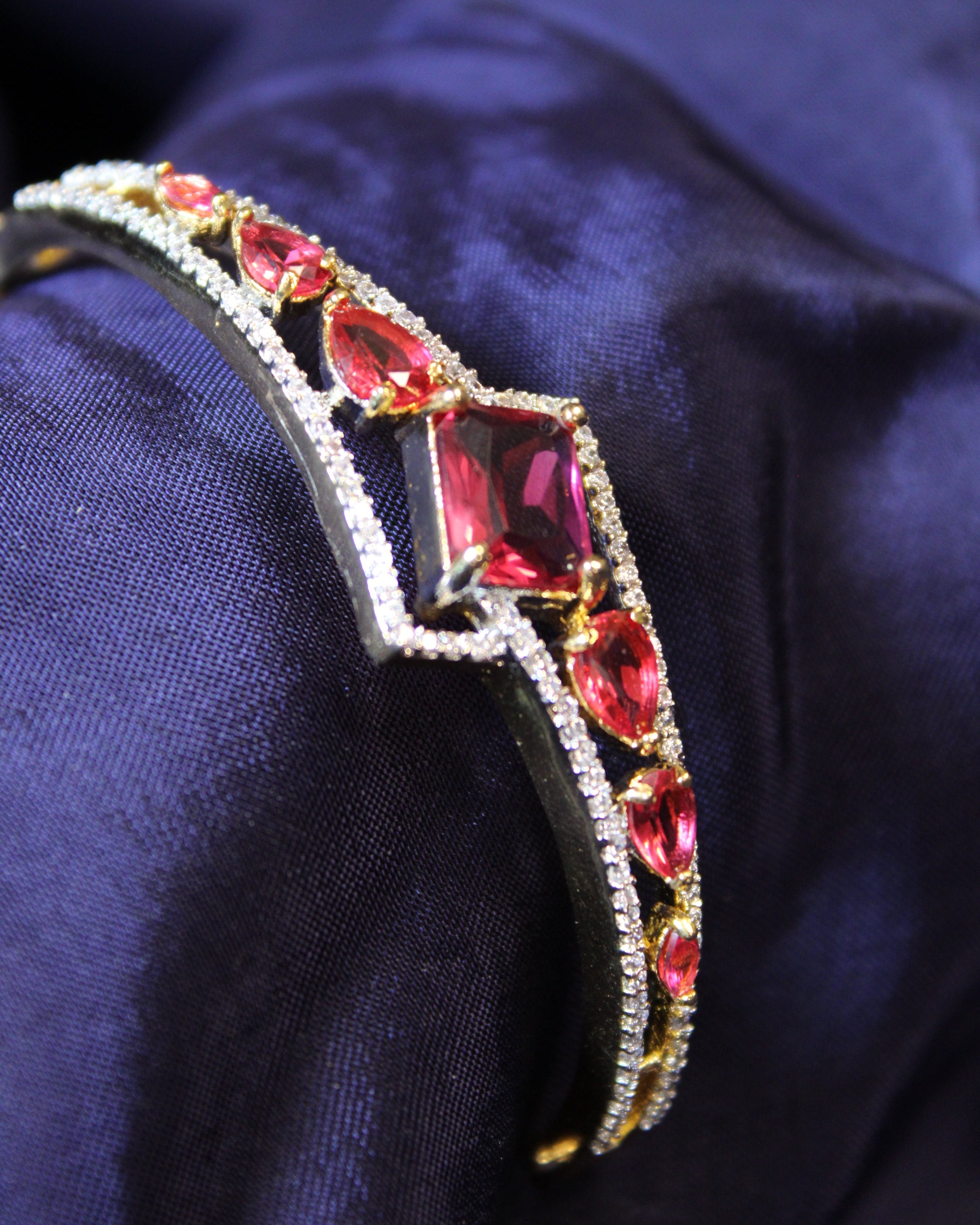 Jeweled bracelet with red gemstones on a dark blue fabric background