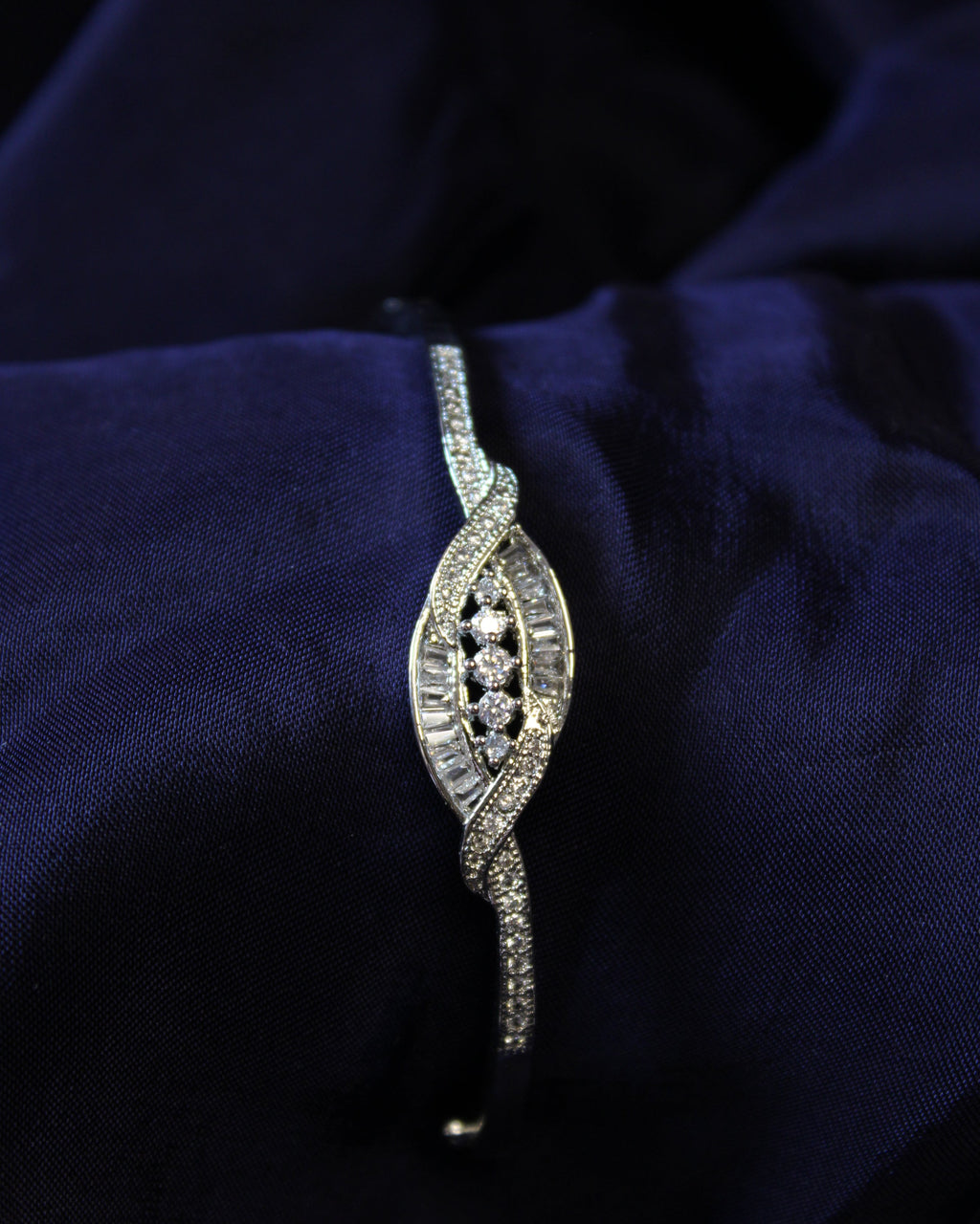 Silver bracelet with diamonds on a dark blue fabric background