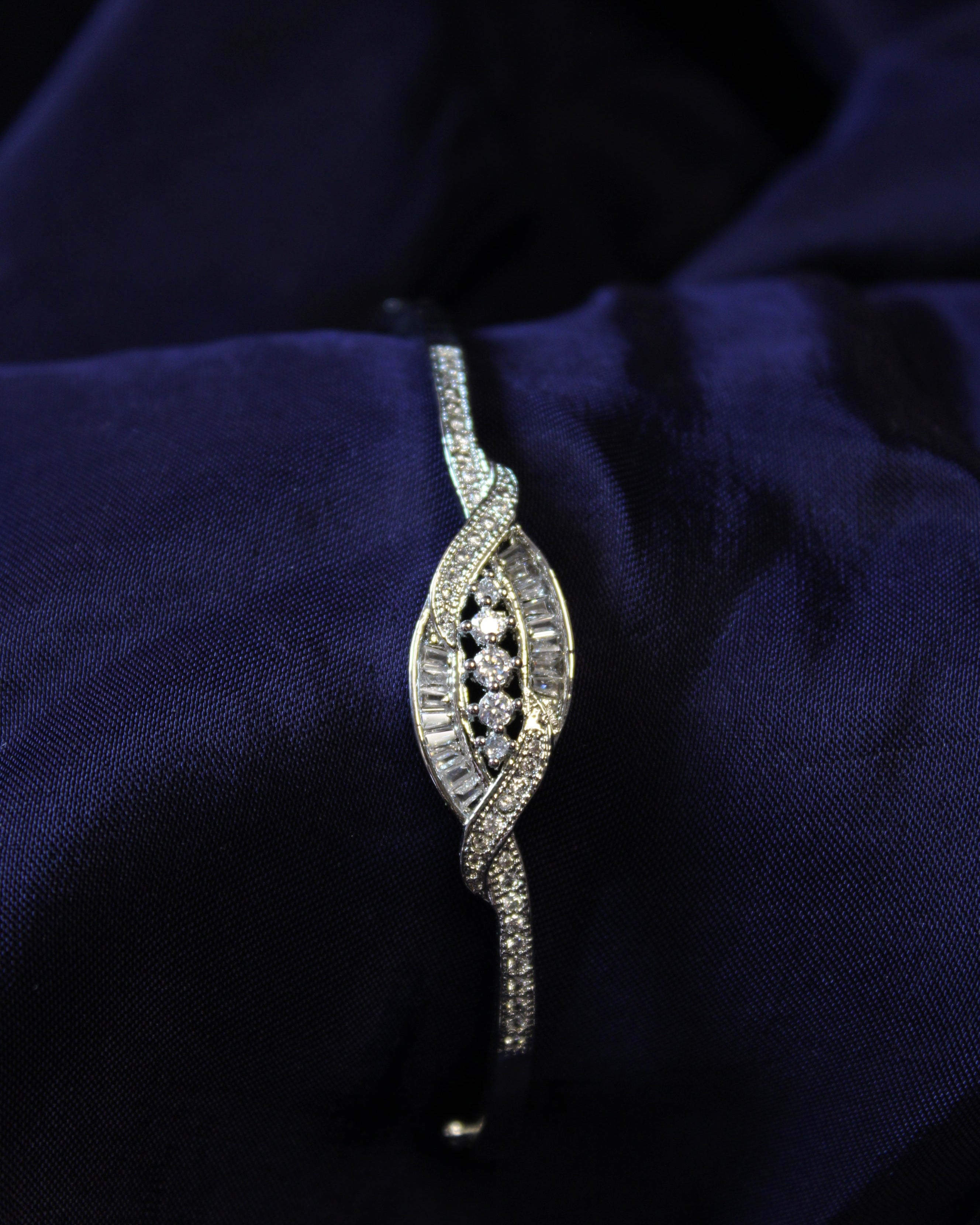 Silver bracelet with diamonds on a dark blue fabric background