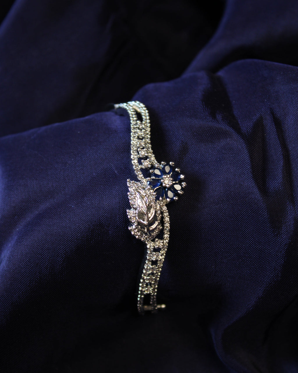 Silver bracelet with a blue gemstone on a dark purple fabric background