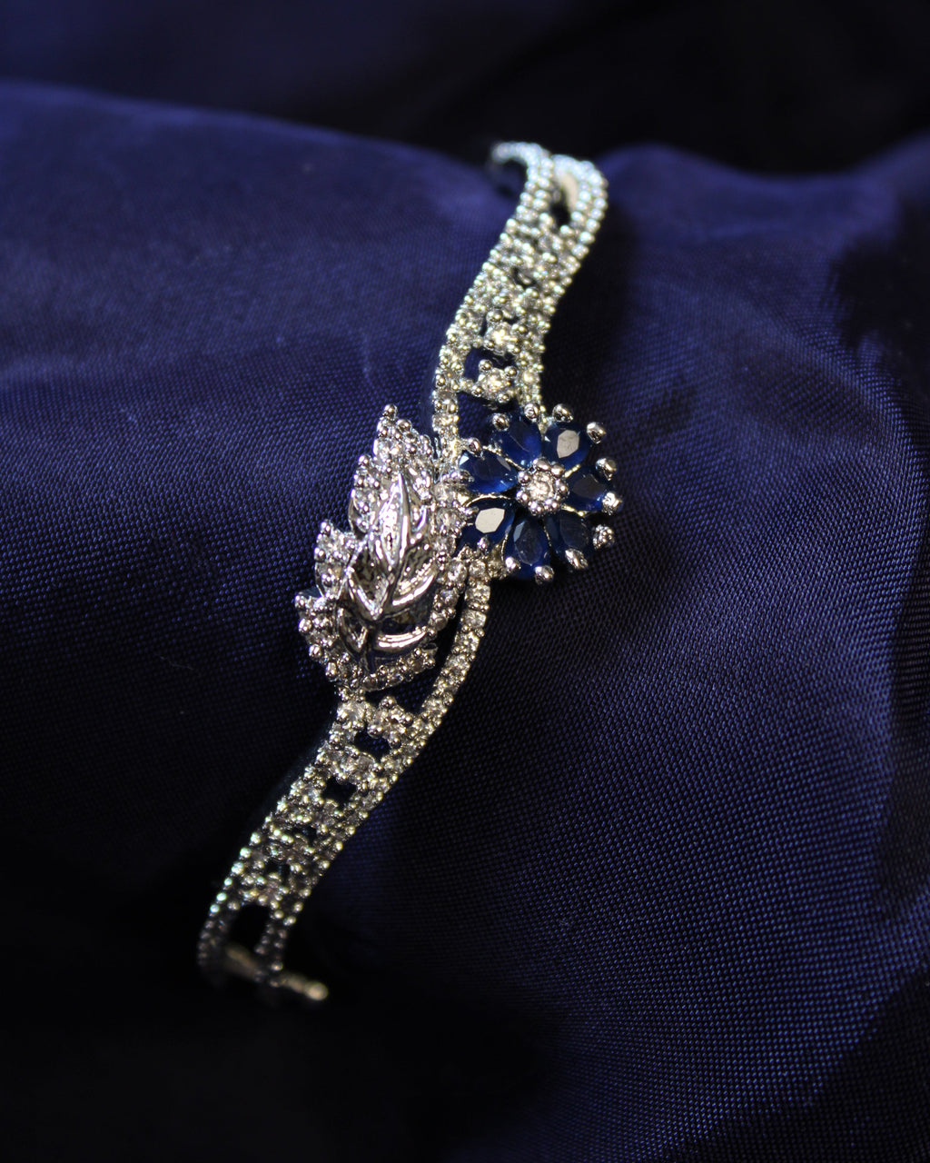 Silver bracelet with a blue gemstone on a dark blue fabric background