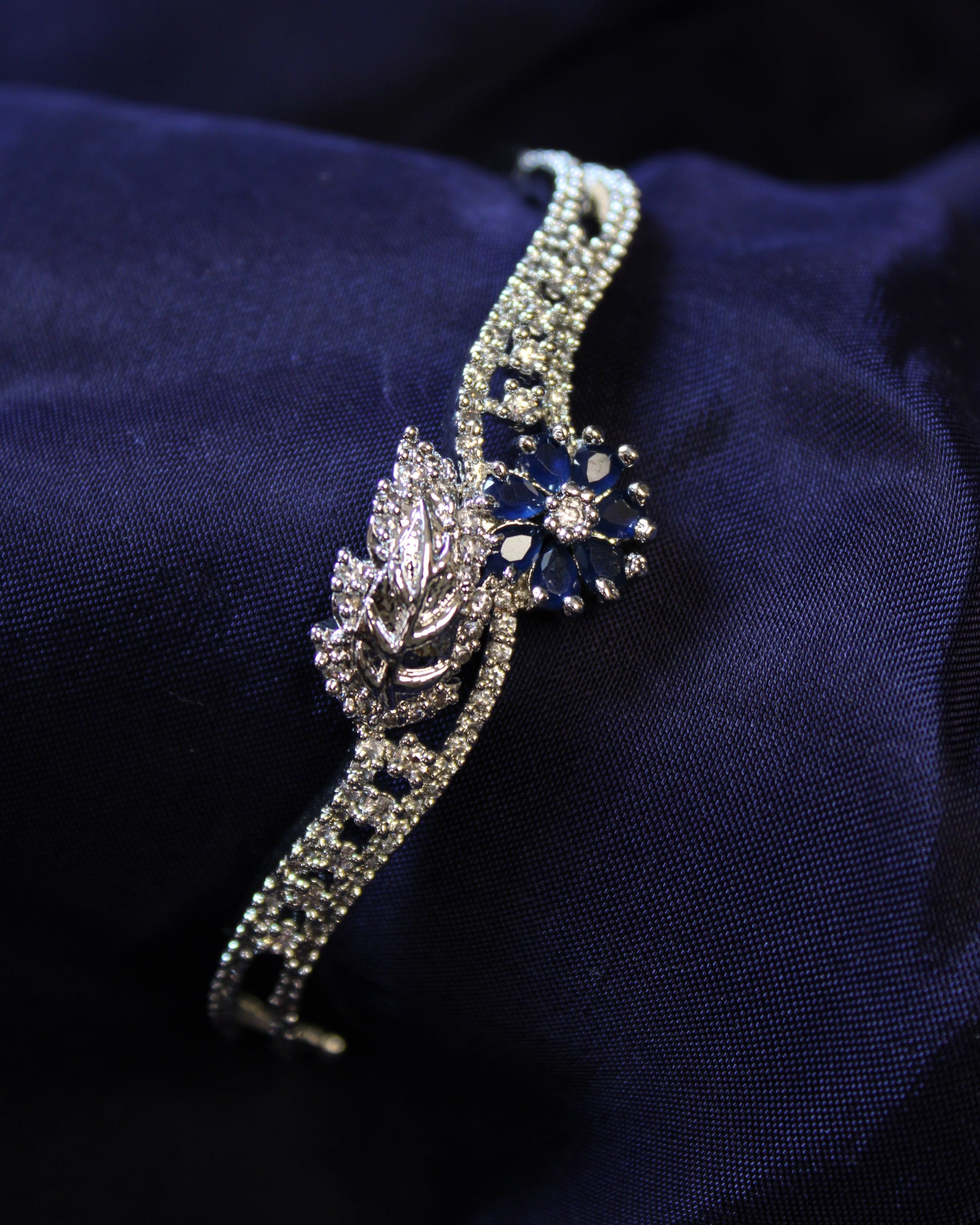 Silver bracelet with a blue gemstone on a dark blue fabric background