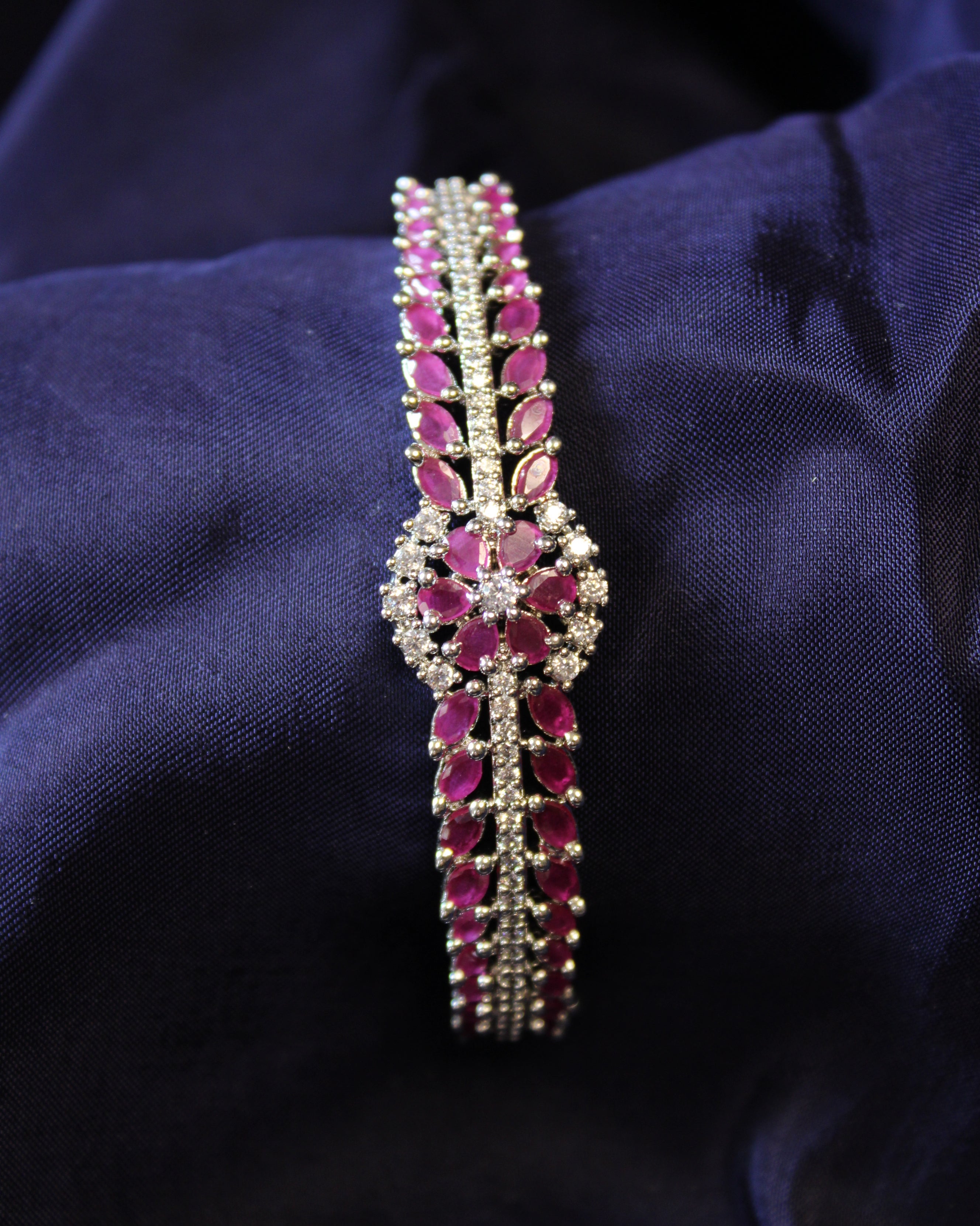 Bracelet with red ruby gemstones on a dark blue fabric background