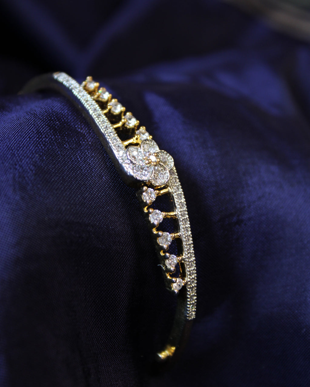 Gold and diamond bracelet on a dark blue fabric background