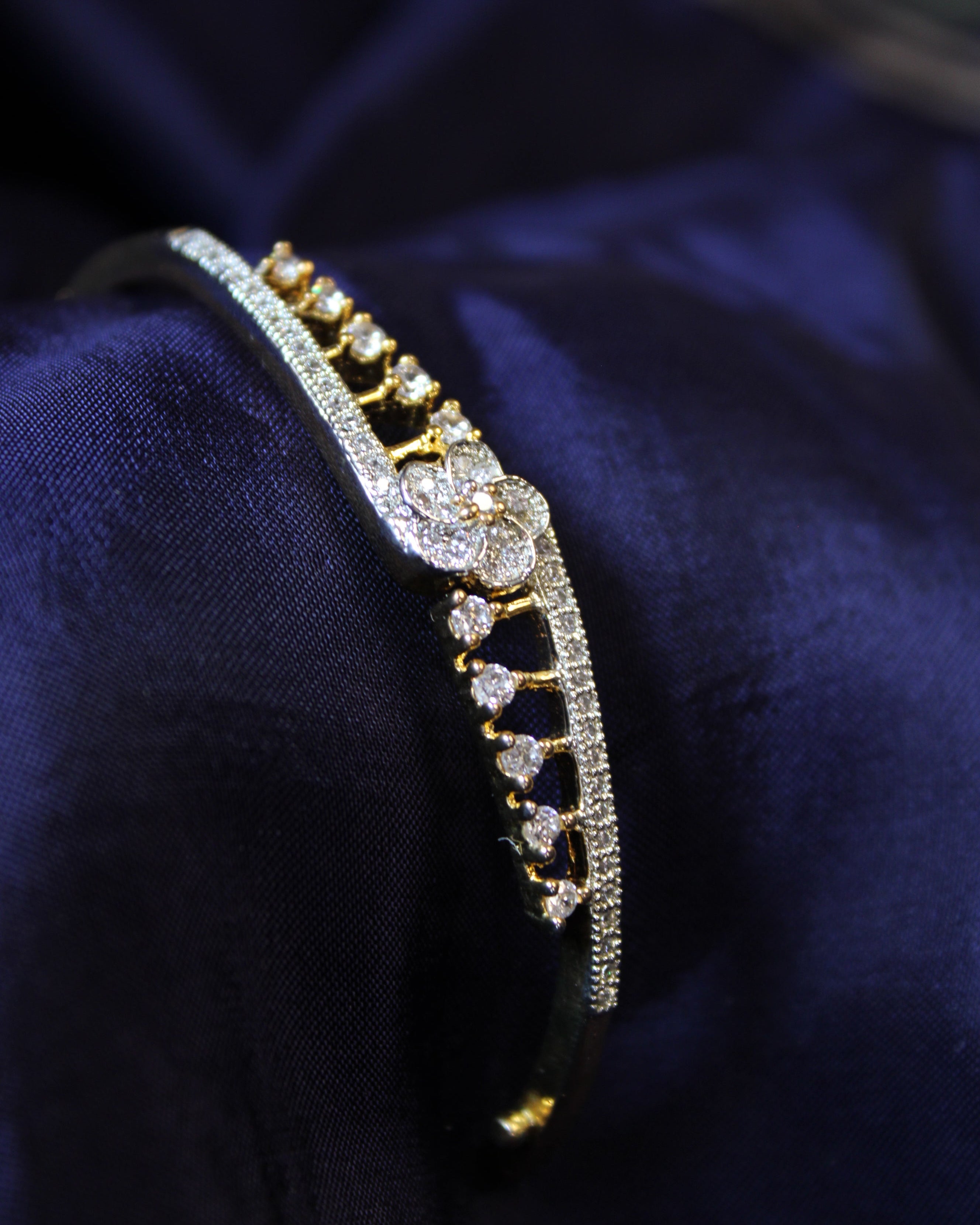 Gold and diamond bracelet on a dark blue fabric background